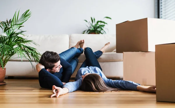 Un jeune couple avec des boîtes en carton se déplaçant dans une nouvelle maison . — Photo