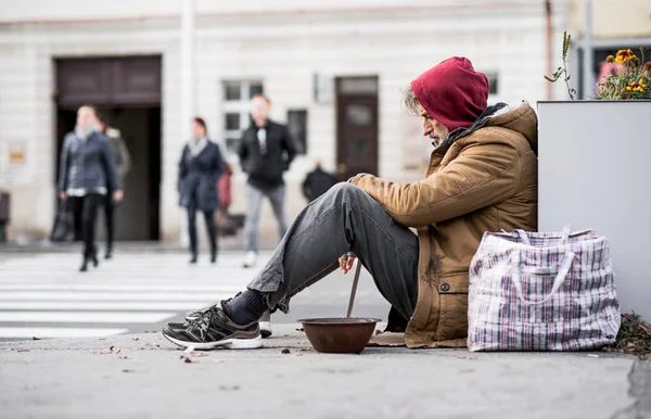 市ではお金を寄付を求めて屋外に座っているホームレス乞食男. — ストック写真