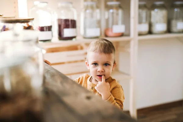 제로 폐기물 상점에 있는 카운터에 서 있는 작은 유아 소년. — 스톡 사진