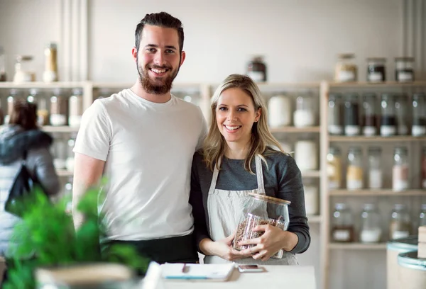 Een portret van twee verkoopster permanent in nul afval winkel, camera kijken. — Stockfoto