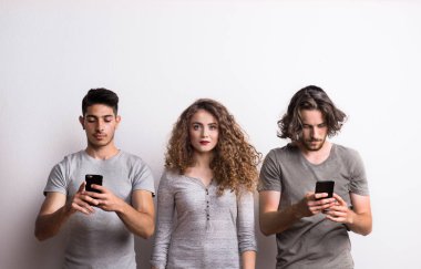 A young woman with two friends occupied with modern technology.