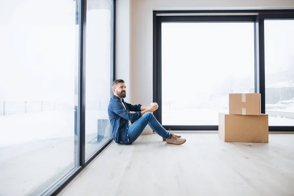 Un homme mûr avec des boîtes en carton assis sur le sol, ameublement nouvelle maison . — Photo