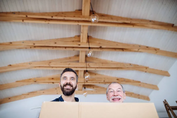 Ein reifer Mann mit seinem älteren Vater, der ein neues Haus, ein neues Wohnkonzept einrichtet. — Stockfoto