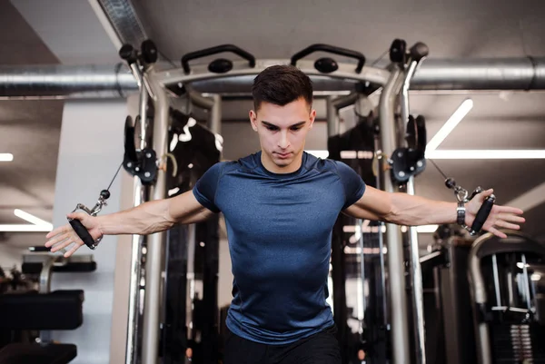 En ung stilig man gör styrka träning träning i gym. — Stockfoto