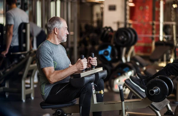 En äldre man gör styrka träning övning i gymmet. Kopiera utrymme. — Stockfoto