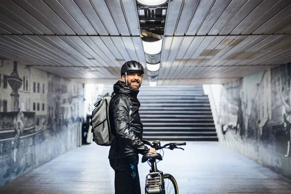 Mensajero de bicicleta masculino de pie en el metro al entregar paquetes en la ciudad . —  Fotos de Stock