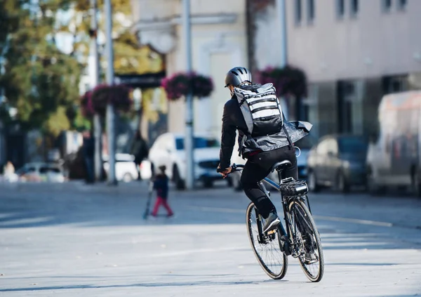 Eine Rückansicht männlicher Fahrradkuriere, die Pakete in der Stadt ausliefern. Kopierraum. — Stockfoto