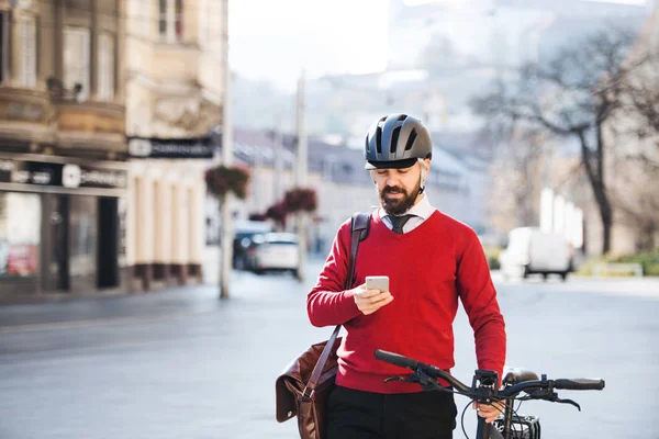 Hipster viajero de negocios con bicicleta y teléfono inteligente en el camino al trabajo en la ciudad . — Foto de Stock