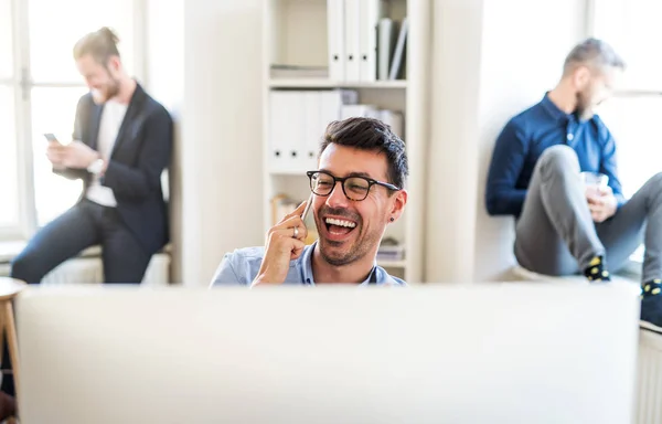 Gruppen av unga företagare med smartphone som arbetar tillsammans i ett modernt kontor. — Stockfoto