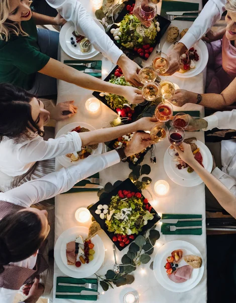 A midsection people sitting at a table on a indoor party, clinking glasses. Top view. — Stock Photo, Image