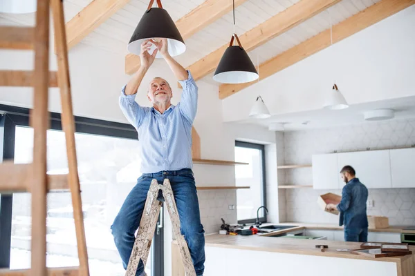 En äldre man att hjälpa sin son med möblera nytt hus, ett nytt hem koncept. — Stockfoto