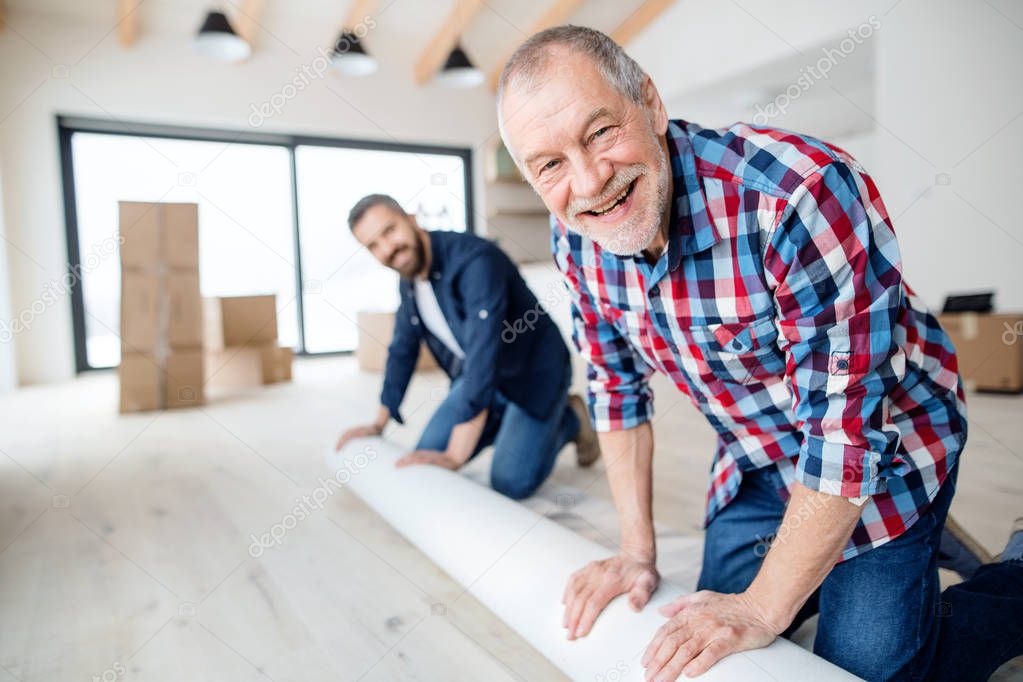 A senior man helping his son with furnishing new house, a new home concept.