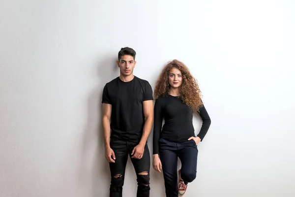 Porträtt av ett ungt par stående i en studio, bär svarta kläder. — Stockfoto