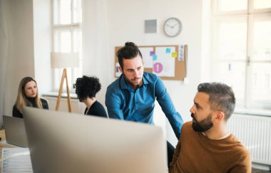 Modern bir ofiste çalışan dizüstü bilgisayar ile Genç İşadamları grubu.