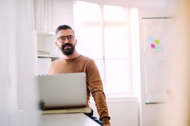 Olgun hipster işadamı modern bir ofiste çalışan dizüstü bilgisayar ile.