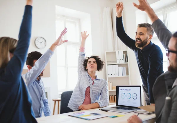 Jóvenes empresarios sentados alrededor de la mesa en una oficina moderna, celebrando el éxito . — Foto de Stock