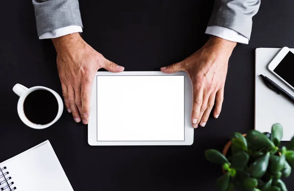 Um meio-termo de um homem de negócios sentado à mesa, usando um tablet. Uma vista superior. Espaço de cópia . — Fotografia de Stock