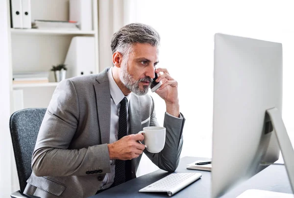 Affärsman med smartphone, kaffe och dator sitter vid bordet, att ringa ett telefonsamtal. — Stockfoto