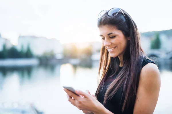 Vacker kvinna i svart klänning stående av en flod i staden Prag, textmeddelanden. — Stockfoto