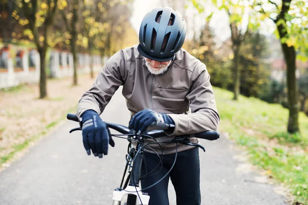 Aktiver Senior mit Elektrofahrrad steht draußen auf einer Straße in der Natur. — Stockfoto