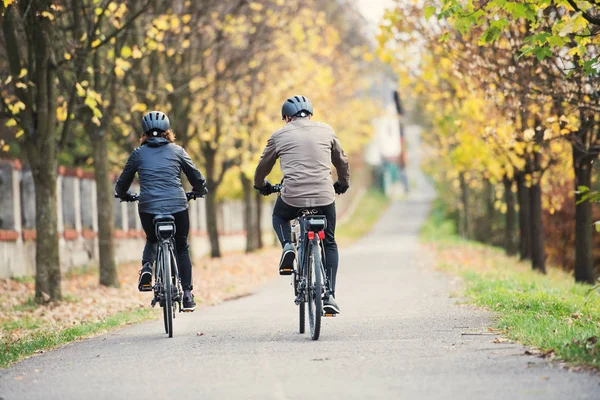 Widok z tyłu starszy para z electrobikes na rowerze w plenerze na drodze. — Zdjęcie stockowe