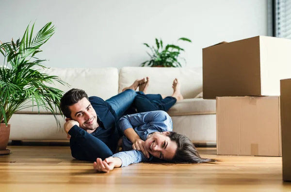 Un jeune couple avec des boîtes en carton se déplaçant dans une nouvelle maison . — Photo