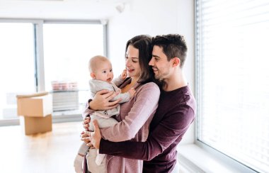 Bir bebek ve karton kutular içinde yeni bir ev taşıma ile genç çift portresi.