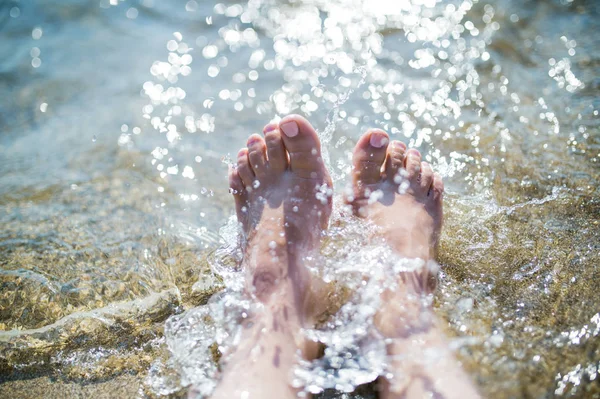 Primo piano dei piedi femminili in acqua sulla spiaggia, concetto di vacanza estiva . — Foto Stock