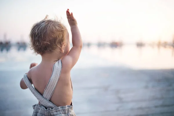 Eine Rückansicht eines kleinen Mädchens, das im Sommerurlaub am Strand steht. — Stockfoto