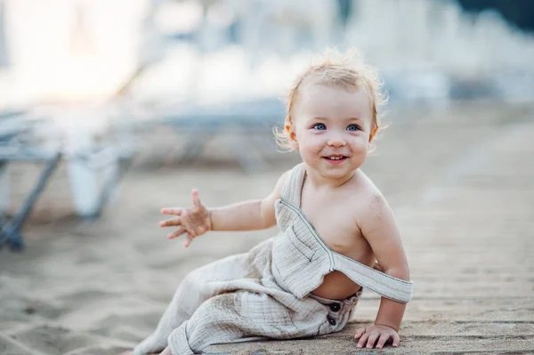 Una piccola bambina seduta sulla spiaggia in vacanza estiva . — Foto Stock