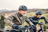 Aktives Seniorenpaar mit Elektrofahrrädern unterwegs in der Natur.