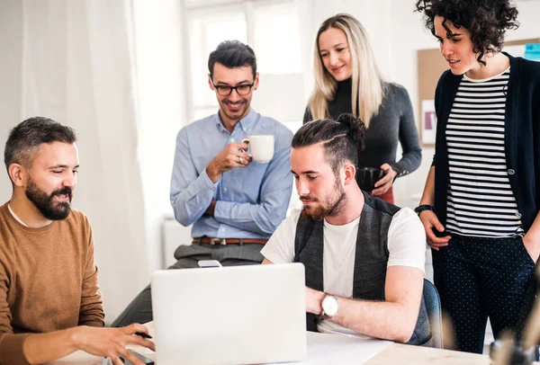 Grupo de jóvenes empresarios alrededor de la mesa en una oficina moderna, teniendo reunión . — Foto de Stock