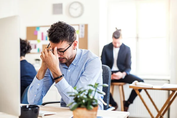 Jeune homme d'affaires frustré avec smartphone travaillant dans un bureau moderne . — Photo
