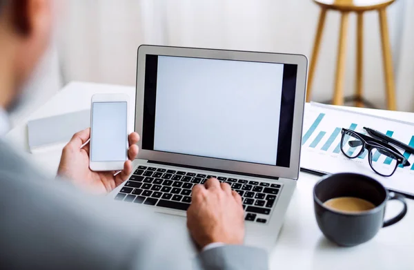 Bránice podnikatel s smartphone a notebook, sedí u stolu, pracovní. — Stock fotografie