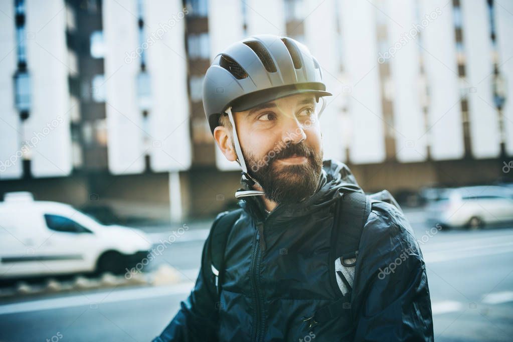 Male courier with bicycle helmet delivering packages in city.