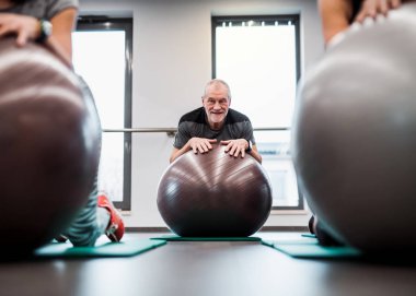 Büyükler uygun topları ile egzersiz yaparak spor salonunda bir grup.