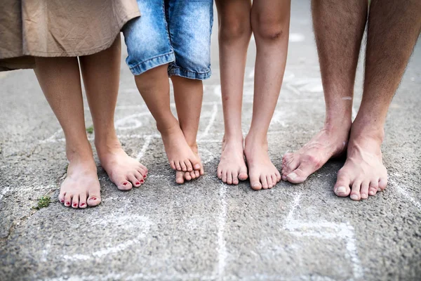 Ein Mittelteil der Beine einer Familie mit zwei kleinen Söhnen, die barfuß auf einer Straße stehen. — Stockfoto