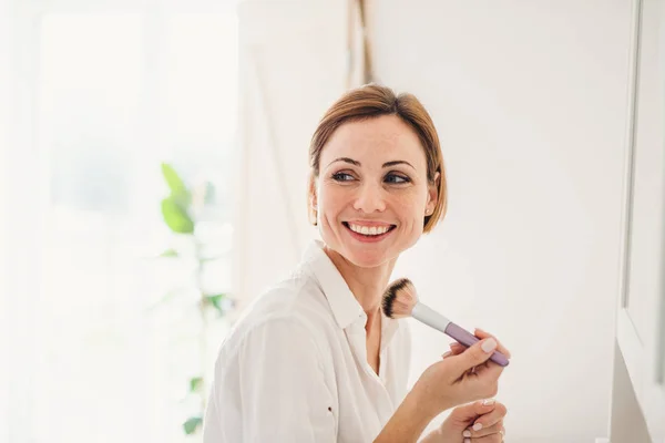 Mladá žena uvedení na make-up ráno v koupelně. — Stock fotografie