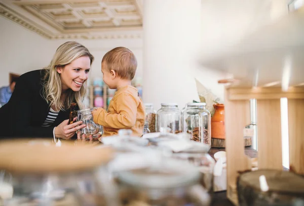 A young woman with a toddler boy buying groceries in zero waste shop. — Stock Photo, Image