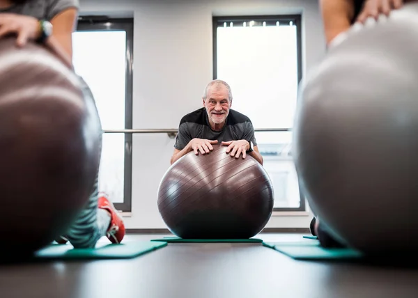 Un grupo de personas mayores en el gimnasio haciendo ejercicio con pelotas en forma . — Foto de Stock