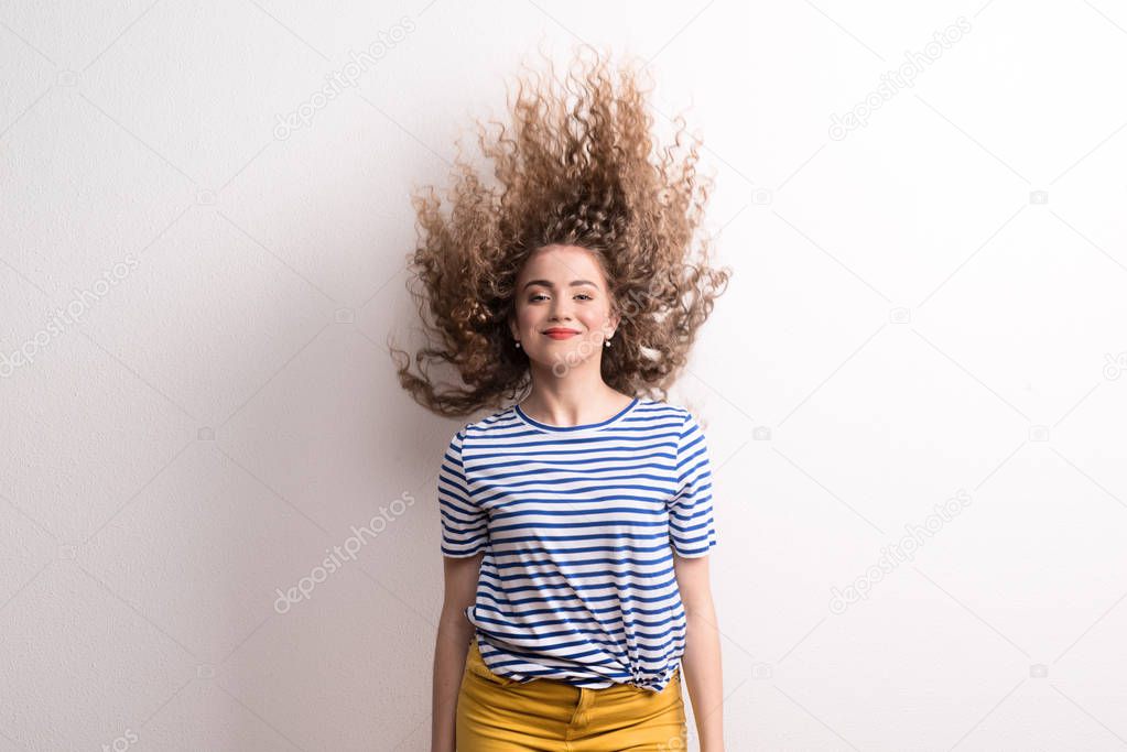 Young beautiful joyful woman with long curly hair in studio, jumping.