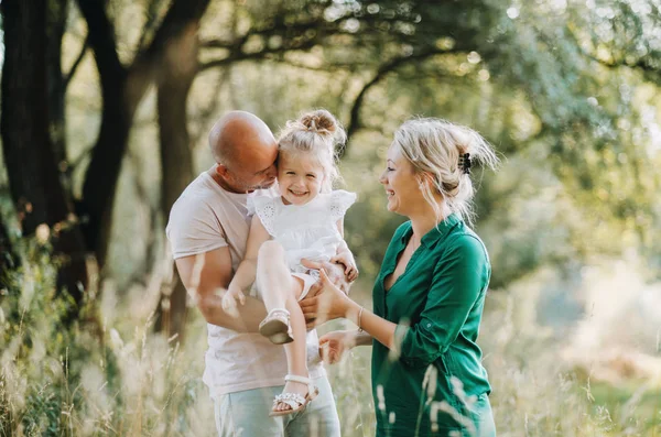 Ung familj med en liten dotter i solig sommar naturen. — Stockfoto