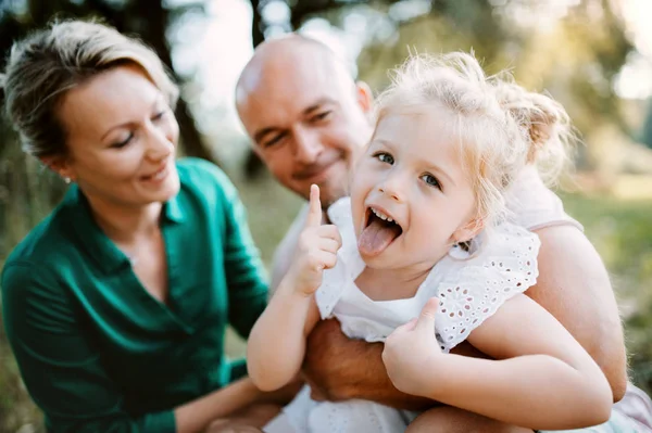 Ung familj med en liten dotter i solig sommar naturen. — Stockfoto