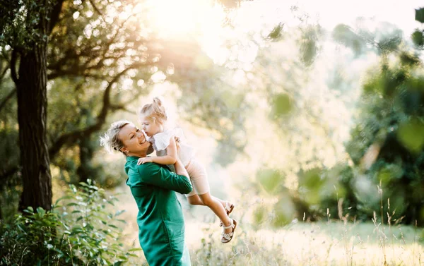 Joven madre en la naturaleza sosteniendo a su pequeña hija en los brazos en verano. Copiar espacio . — Foto de Stock