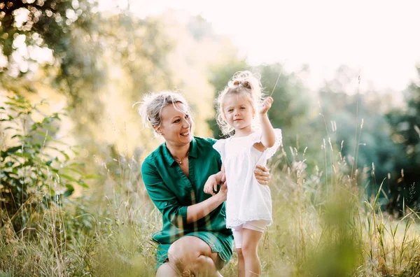 Giovane madre in natura che tiene piccola figlia in estate . — Foto Stock