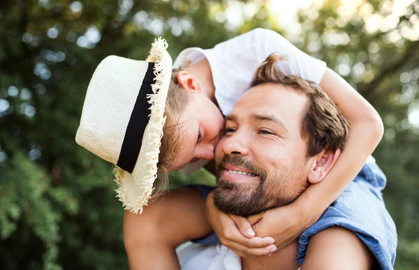 Young father in nature giving small son a piggyback ride. — Stock Photo, Image