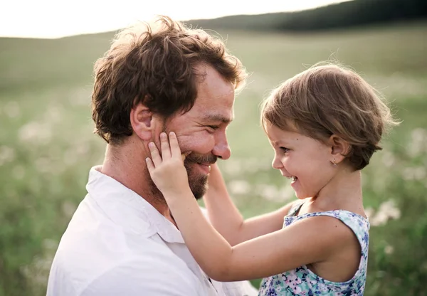 Young father in nature holding small daughter in the arms. — Stock Photo, Image
