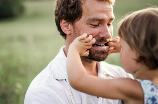 Jovem pai na natureza segurando pequena filha nos braços . — Fotografia de Stock