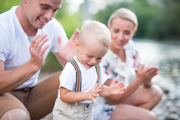 Um menino pequeno da criança com seus pais fora na natureza ensolarada do verão, aplaudindo . — Fotografia de Stock