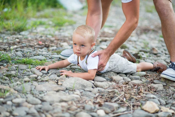 Onherkenbaar vader opheffing van de zoon van een kleine peuter in de zonnige zomer natuur. — Stockfoto